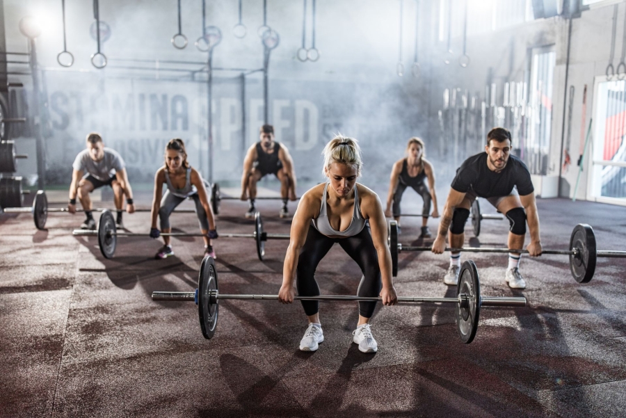 group of people exercising deadlift with barbells in a gym