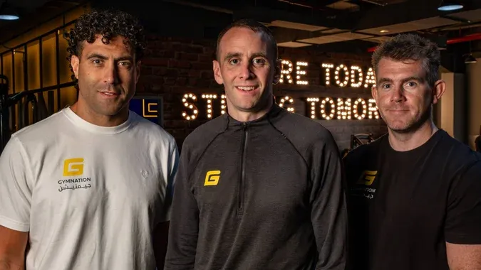 three men in gym clothes with logo smiling